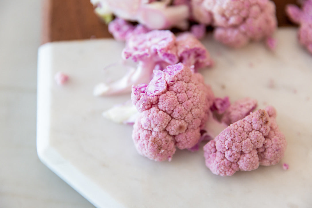 Nutrition by Gina; picture of pink cauliflower cut up on a marble cutting board.